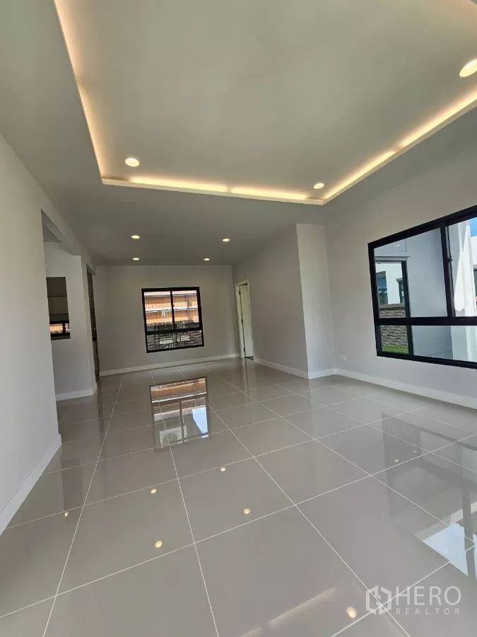 Detached House for sale in Lam Luk Ka, Pathum Thani - Bright open-plan living room with recessed lighting and glossy tiled floors.