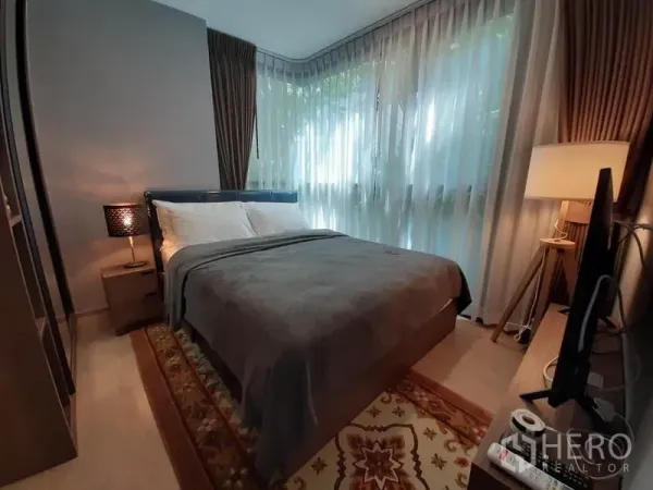 公寓 出租或出售在Watthana, Bangkok - 主卧设大转角落地窗与纱帘，床侧台灯温馨。
