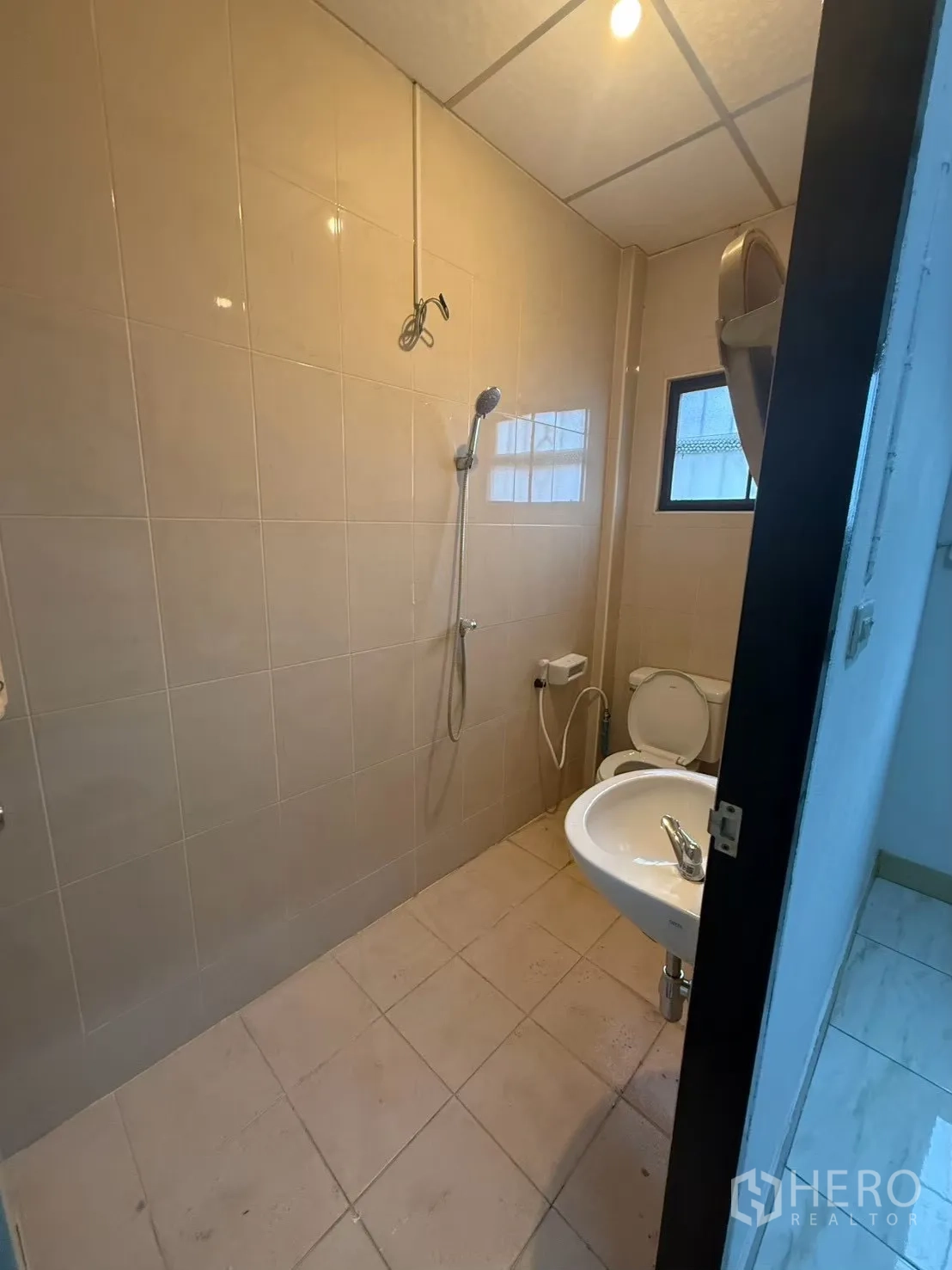 Shophouse for rent in Pak Kret, Nonthaburi - Shower room with beige tiles, toilet, and sink.