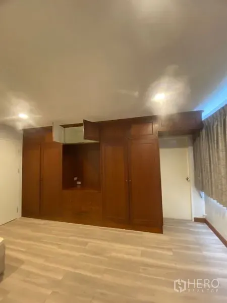 Condominium for rent in Sathon, Bangkok - Bedroom wall featuring built-in wooden wardrobes with recessed lighting and ample storage.