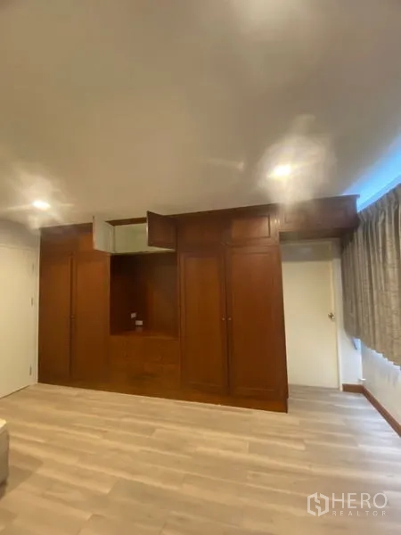 Condominium for rent in Sathon, Bangkok - Bedroom wall featuring built-in wooden wardrobes with recessed lighting and ample storage.