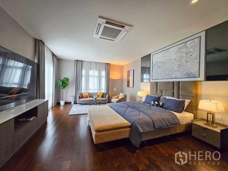 Detached House for rent or sale in Lat Krabang, Bangkok - Spacious master bedroom with king bed, seating area, and warm wood flooring.