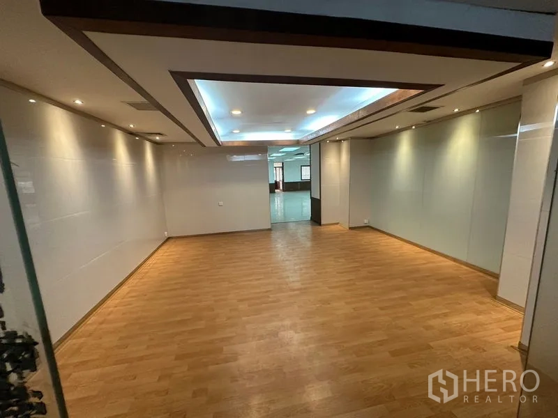 办公空间 出租在Watthana, Bangkok - 开放式办公区，木纹地板、筒灯与玻璃隔断，靠近Asok。