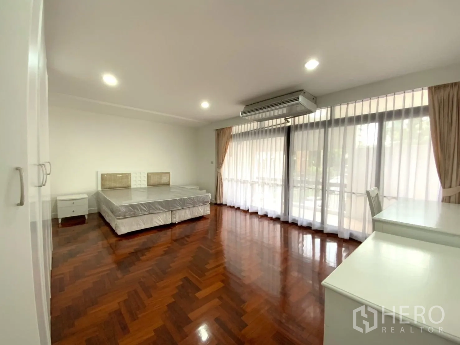 公寓 出租在Watthana, Bangkok - 宽敞卧室，拼花木地板，大幅窗帘窗、空调与特大床。