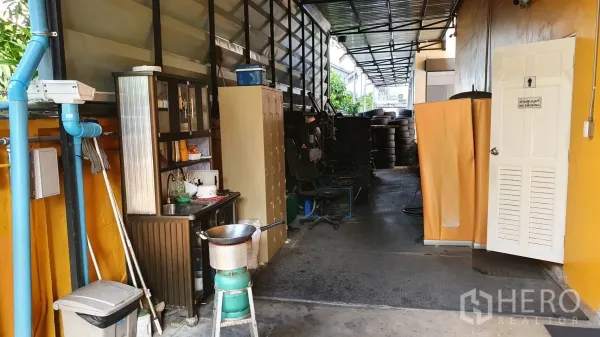 Home Office for rent in Phra Khanong, Bangkok - Covered side corridor with storage lockers, sink area, and stacks of tires.