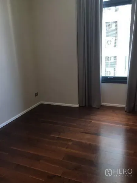 公寓 出租在Watthana, Bangkok - 第二卧室空房，深色木地板，带窗帘的高窗。