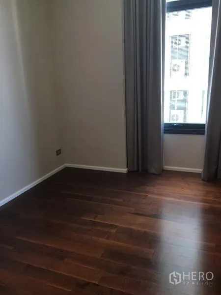 公寓 出租在Watthana, Bangkok - 第二卧室空房，深色木地板，带窗帘的高窗。
