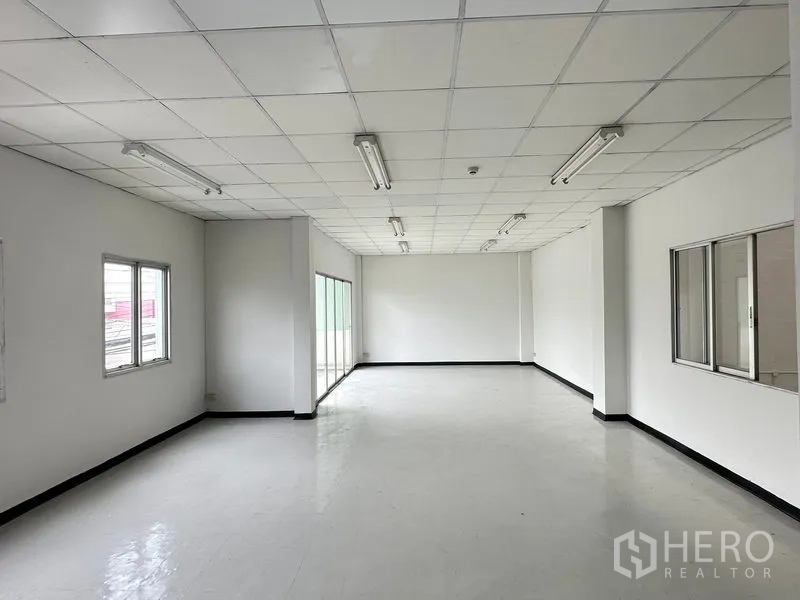 Factory for rent in Khlong Luang, Pathum Thani - Bright upstairs office room with drop ceiling, fluorescent lighting and multiple windows.