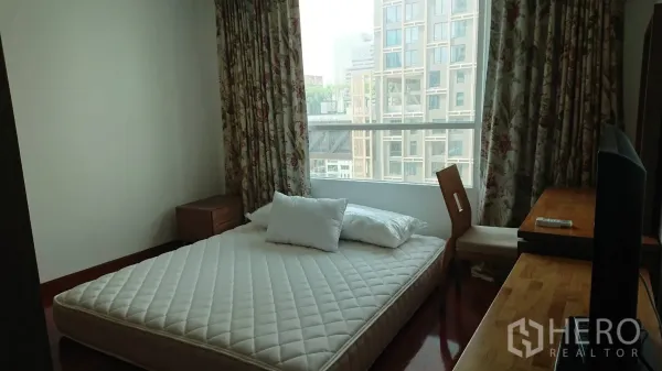 公寓 出租在Pathum Wan, Bangkok - 卧室配大窗与花纹窗帘，低床架加床垫及木质书桌。