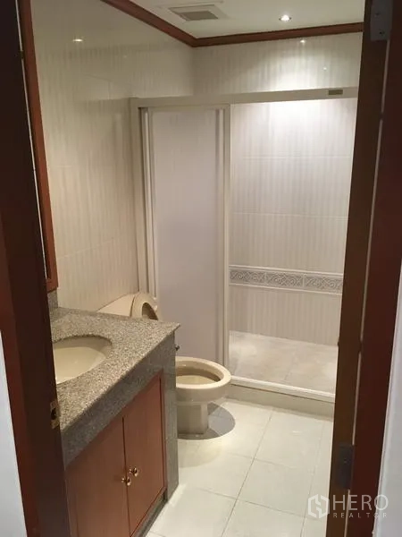 Condominium for rent in Sathon, Bangkok - Bathroom with granite-top vanity, toilet and glass-enclosed shower.