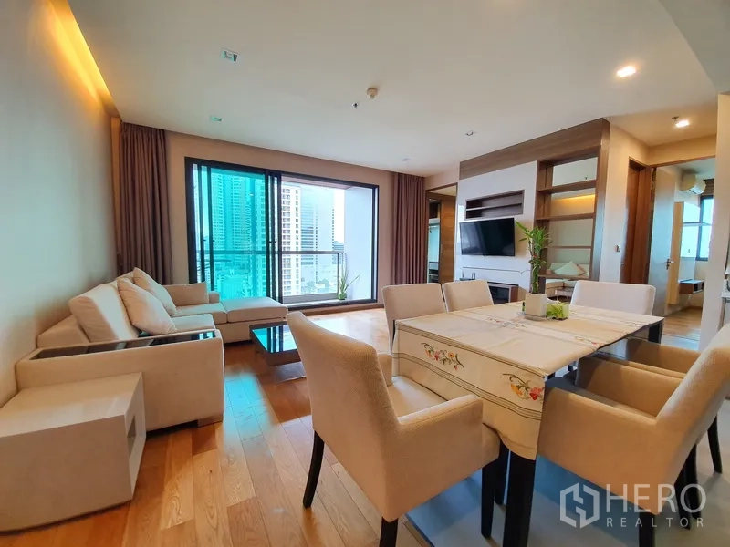 Condominium for rent in Bang Rak, Bangkok - Open-plan living and dining room with sofa set, dining table, and a balcony city view in a modern Bangkok condo.
