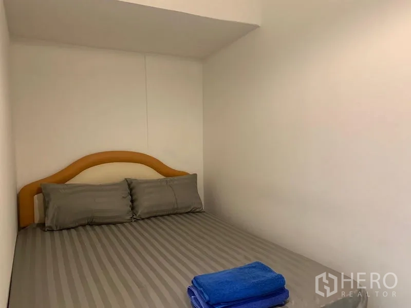 Shophouse for rent in Khlong Toei, Bangkok - Small guest room with a double bed and gray bedding.