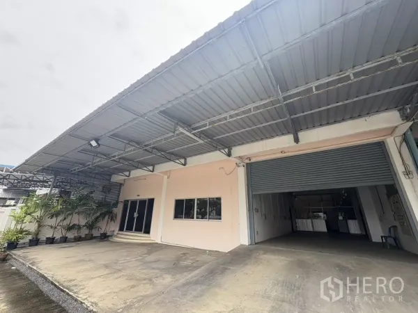 货栈 出租在Bang Phli, Samut Prakan - 仓库外立面，带雨棚的装卸区与玻璃办公入口及卷闸门