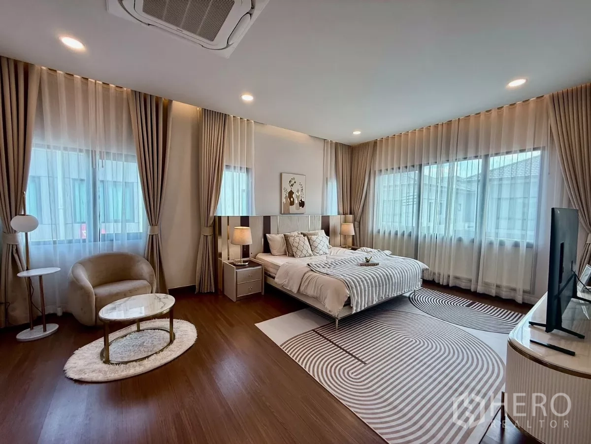 独立式住宅 出租在Bang Phli, Samut Prakan - 主卧带休闲角，大窗与柔和窗帘。