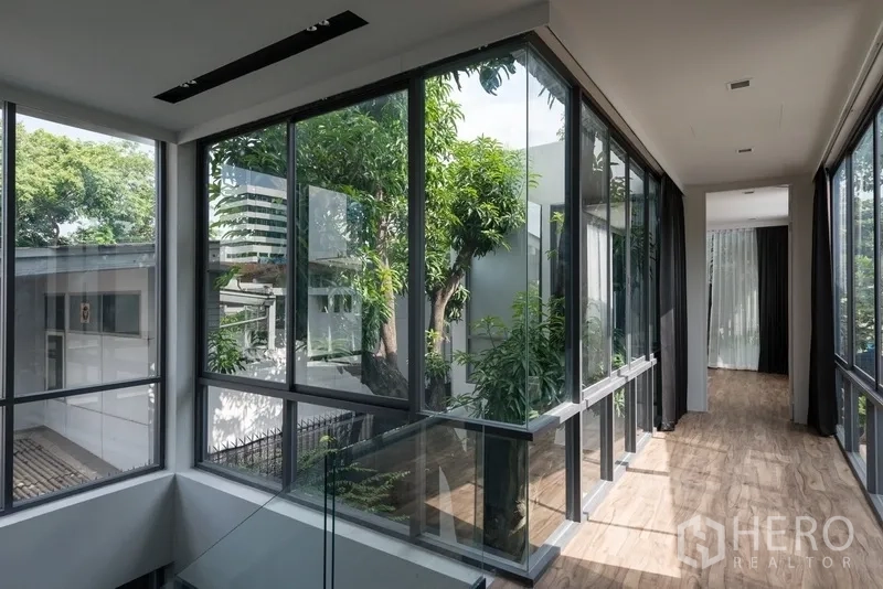 办公空间 出租在Watthana, Bangkok - 二层玻璃走廊，眺望绿树与城市景观。