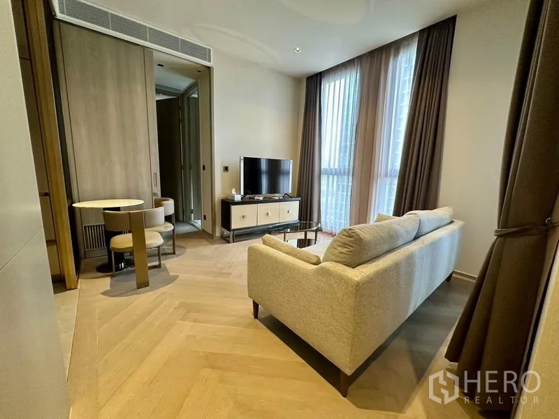 Condominium for rent - Living room angle showing sofa, TV stand, tall curtains, and herringbone wood flooring.