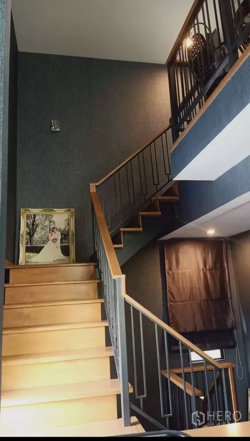 Detached House for rent or sale in Khan Na Yao, Bangkok - Wood staircase with metal railing leading to upper floors in a high-ceiling hall.