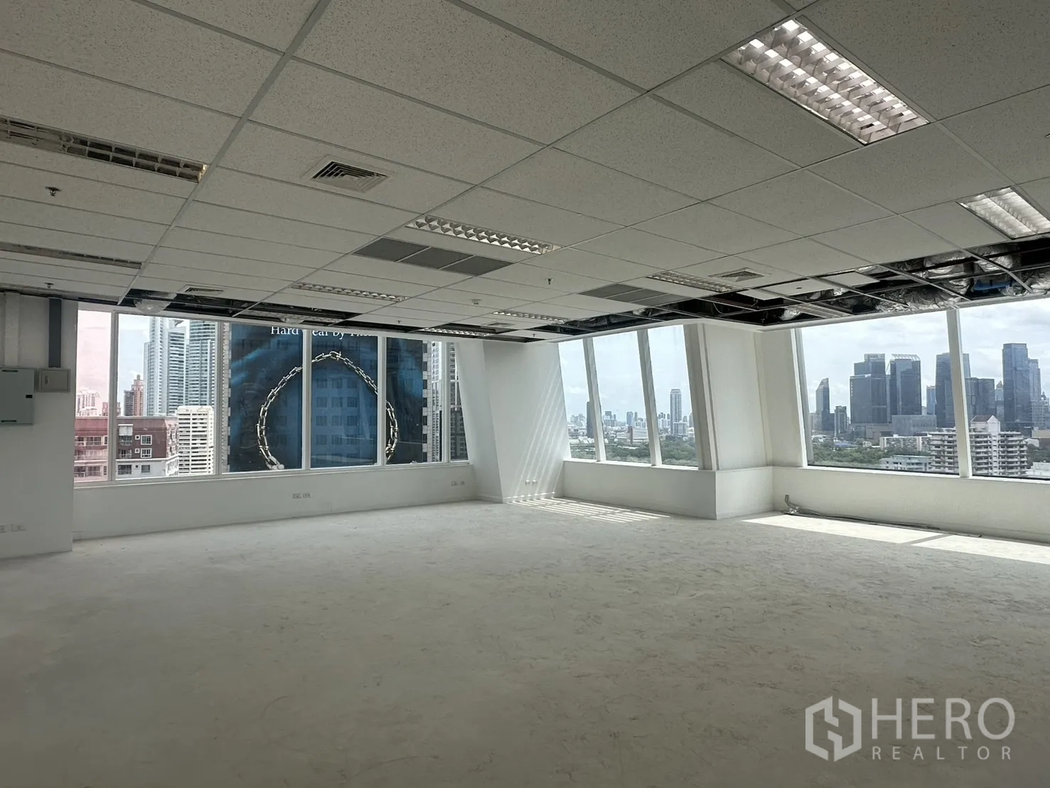 Office Space for rent in Watthana, Bangkok - Bright workspace with wrap-around windows and fluorescent lighting, ready for tenant fit-out.