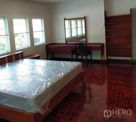 Apartment for rent in Pathum Wan, Bangkok - Bedroom angle showing dressing table, mirror, shelving and large windows over parquet floors.