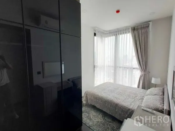Condominium for rent in Watthana, Bangkok - Corner bedroom with floor-to-ceiling windows and a glossy wardrobe.