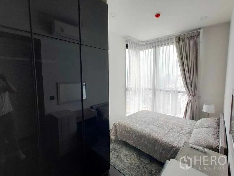 Condominium for rent in Watthana, Bangkok - Corner bedroom with floor-to-ceiling windows and a glossy wardrobe.