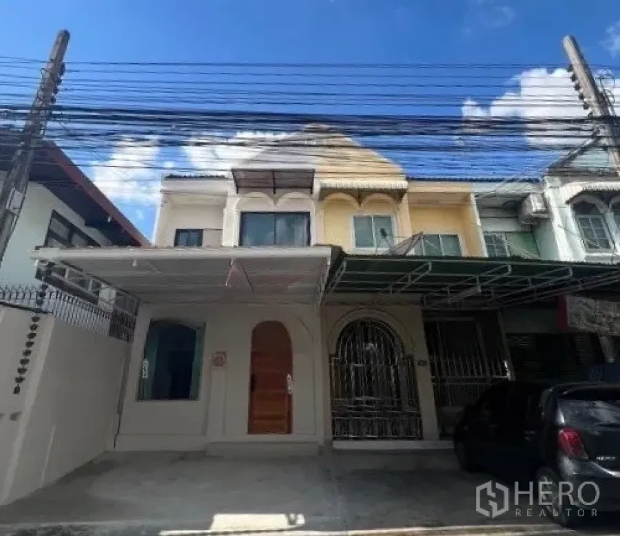Townhouse for rent or sale in Phra Khanong, Bangkok - Covered carport with arched window and wooden front door.