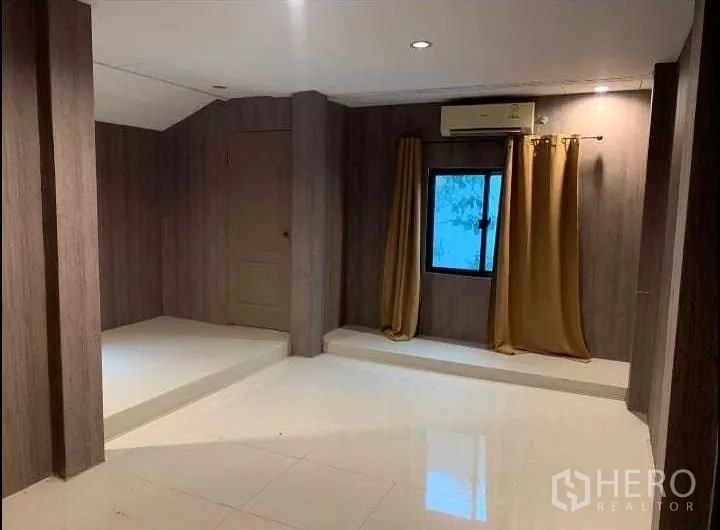 Detached House for rent or sale in Wang Thonglang, Bangkok - Versatile room with wood-panel walls, white tile floor, small window and AC unit.