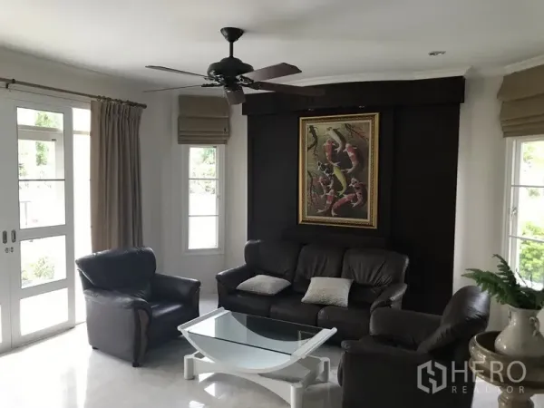 独立式住宅 出租在Phra Khanong, Bangkok - 客厅配皮沙发、吊扇与推拉门，采光充足通向花园。