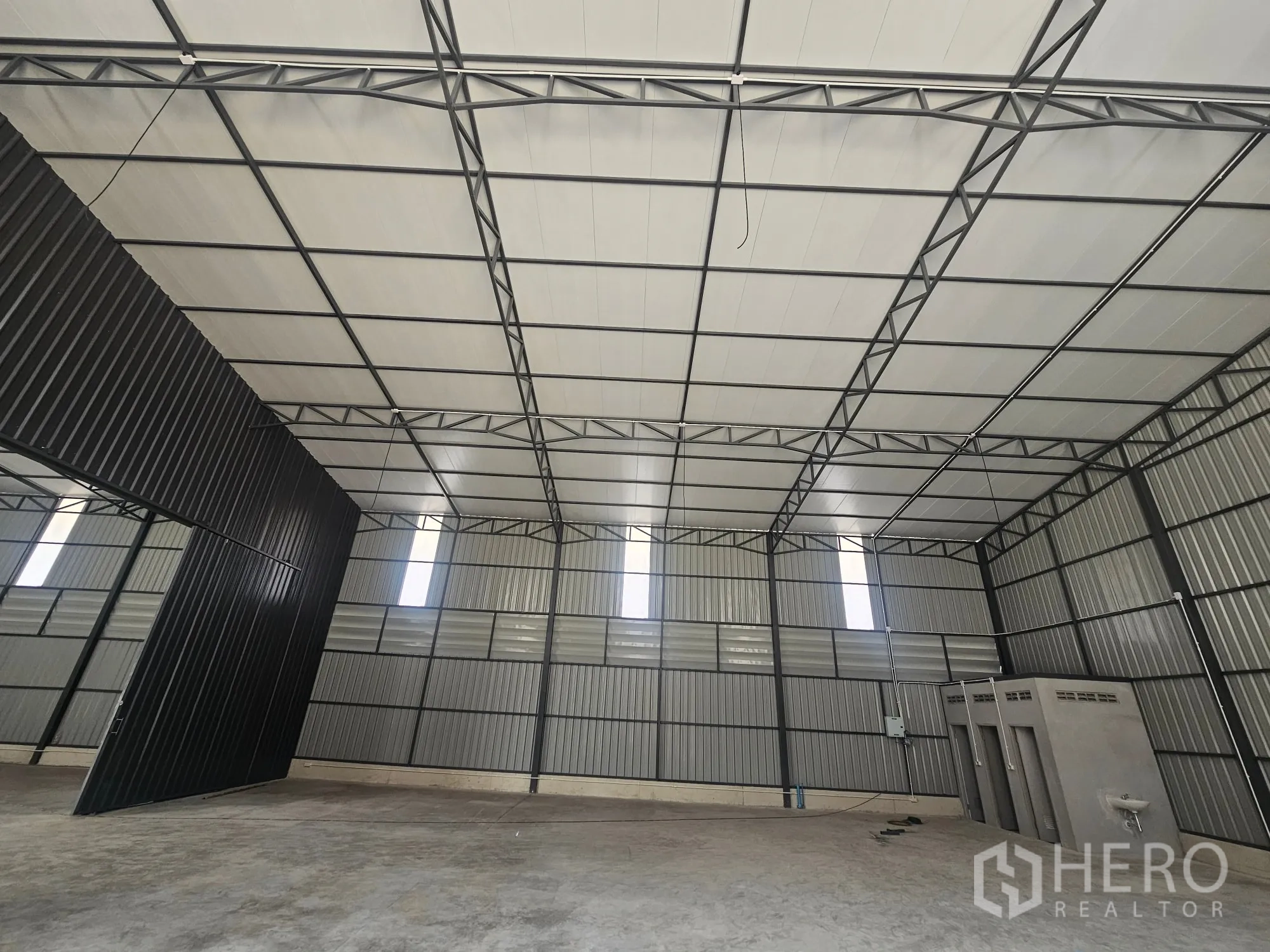 仓库 for rent in Bang Khen, Bangkok - 仓库内部高钢桁架屋顶、混凝土地面与大型入口门。