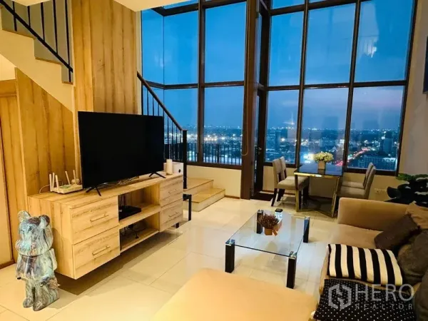 公寓 出租在Bangkok - 客厅配电视柜与玻璃茶几，整面落地窗观夜景