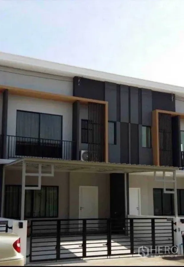 Townhouse for rent in Suan Luang, Bangkok - Modern two-storey townhouse facade with gated parking and small balconies.