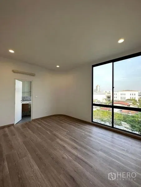 Townhouse for rent in Yan Nawa, Bangkok - Sunlit bedroom with wood flooring, large picture window and ensuite access.