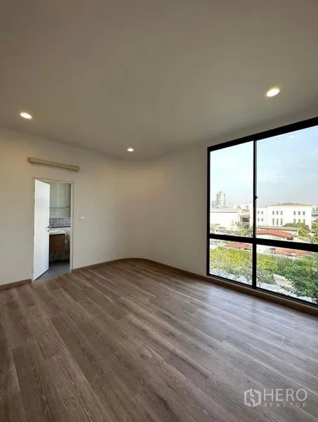 Townhouse for rent in Yan Nawa, Bangkok - Sunlit bedroom with wood flooring, large picture window and ensuite access.