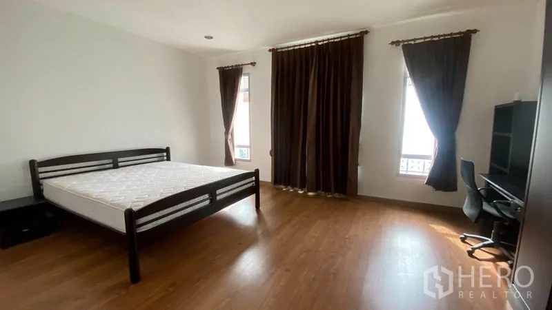 联排别墅 出租在Wang Thonglang, Bangkok - 宽大的主卧，床、书桌、大衣柜和遮光窗帘。