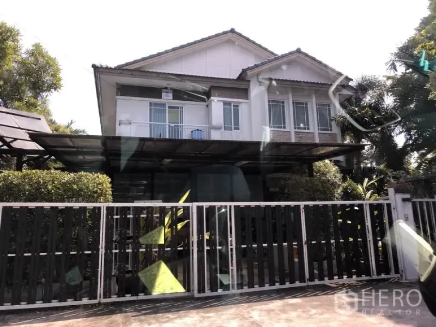 独立式住宅 出售在Bang Kapi, Bangkok - Bang Kapi 两层独栋住宅，带推拉金属围栏、带顶车棚、大面积窗户与前庭绿植。