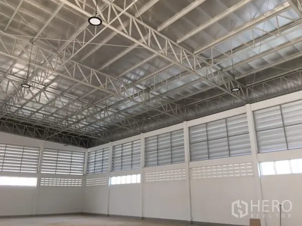 货栈 出租在Nong Chok, Bangkok - 开阔的仓库地面，金属屋顶结构与高棚灯，墙面环绕通风窗。