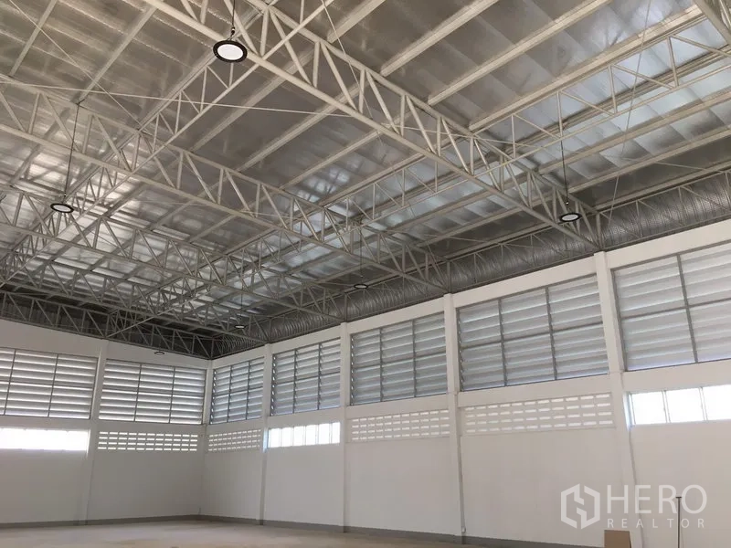 货栈 出租在Nong Chok, Bangkok - 开阔的仓库地面，金属屋顶结构与高棚灯，墙面环绕通风窗。