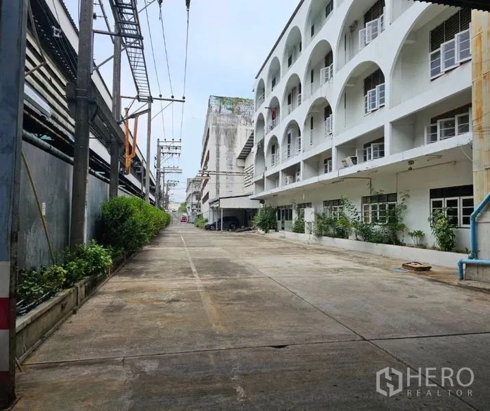 工厂 出租在Bang Kho Laem, Bangkok - 私家通道，道路两侧为建筑、绿化与电线杆。