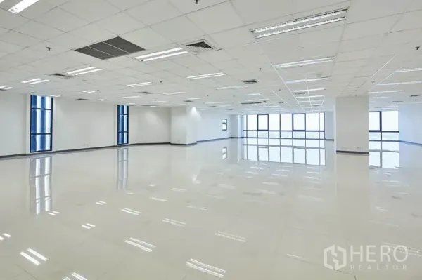 办公空间 出租在Bang Na, Bangkok - 明亮的开放式办公区，格栅吊顶、LED照明、亮面地砖与大尺寸蓝框窗户。