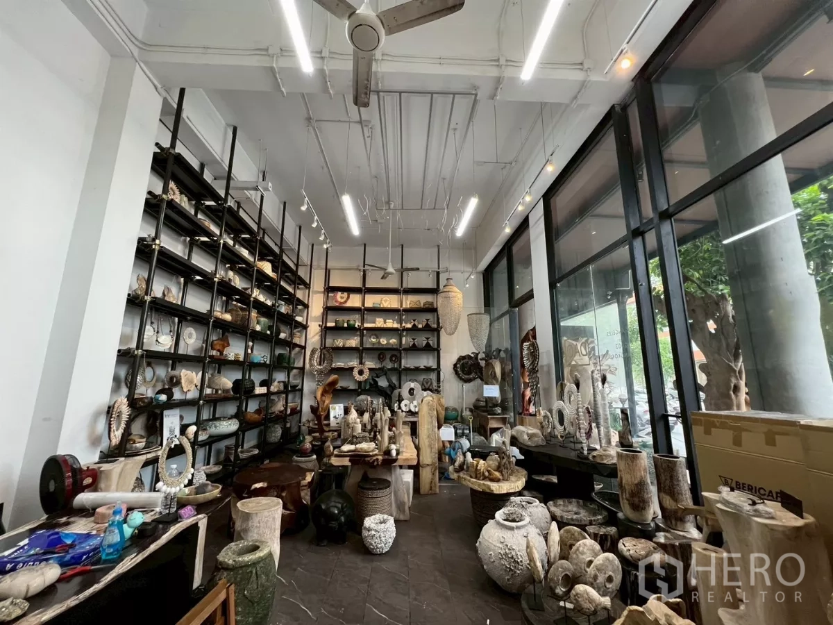 Retail Space for rent in Watthana, Bangkok - High-ceiling Thonglor retail unit with floor-to-ceiling glass, black metal shelving, track lighting, and polished floors facing the street.