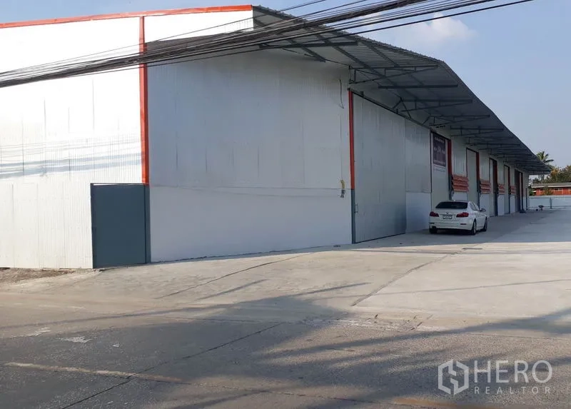 คลังสินค้า ให้เช่าในMueang Pathum Thani, Pathum Thani - อาคารโกดังหลายยูนิตสีขาว มีชายคากว้างและที่จอดรถตลอดแนวถนนคอนกรีต