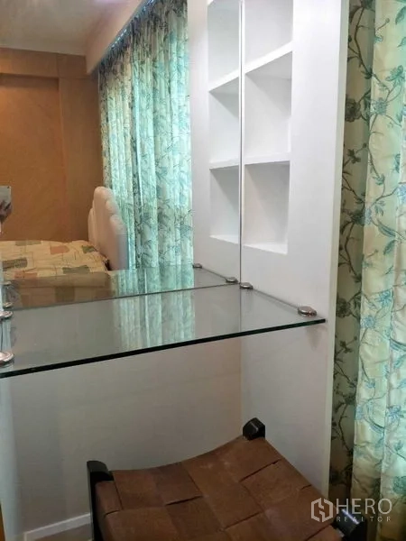 公寓 出租或出售在Watthana, Bangkok - 紧凑化妆/书写角，玻璃台面与墙面置物架相邻窗帘。