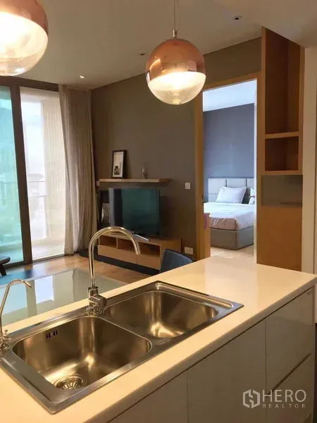 Condominium for rent in Watthana, Bangkok - Open-plan kitchen with island and double sink looking toward the living room and entry to the bedroom.