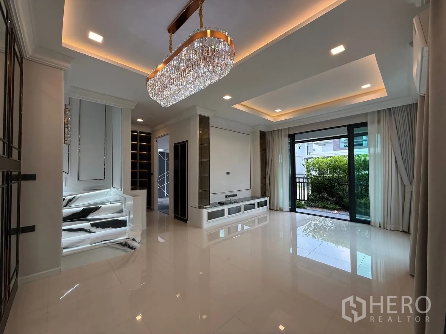 Detached House for sale in Bang Kruai, Nonthaburi - Bright living room with crystal chandelier, recessed lighting, glossy floors and sliding doors to the garden.
