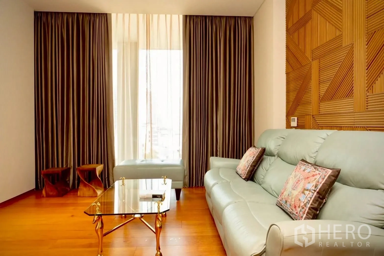 公寓 for sale in Sathon, Bangkok - 起居角落配浅色皮沙发、玻璃茶几与几何木饰墙。