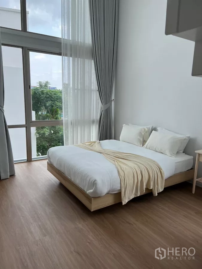 Detached House for rent in Saphan Sung, Bangkok - Bedroom with floor-to-ceiling corner windows and a minimalist platform bed.