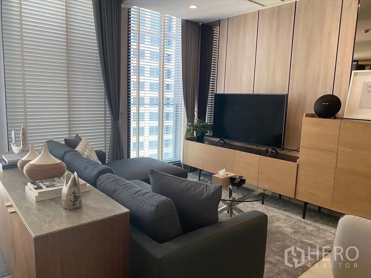公寓 for rent in Pathum Wan, Bangkok - 客厅设灰色转角沙发、电视柜与高窗百叶，采光充足。