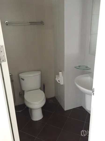 Condominium for rent in Khlong Toei, Bangkok - Tiled bathroom with toilet, pedestal sink and towel bar in a compact layout.
