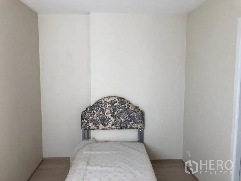 Townhouse for rent in Suan Luang, Bangkok - Compact single bedroom with an upholstered floral headboard.
