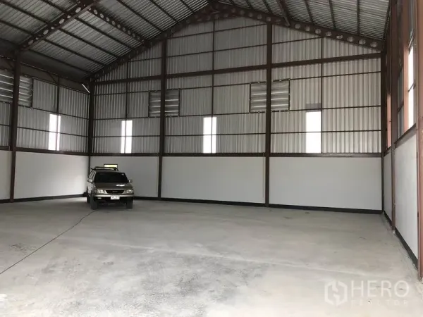 Factory for rent or sale in Sai Noi, Nonthaburi - Large warehouse interior with steel frame walls and ample floor space for vehicles or storage.